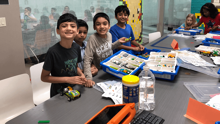 4 kids are standing and showing prototypes of what they built on iCode School Classroom