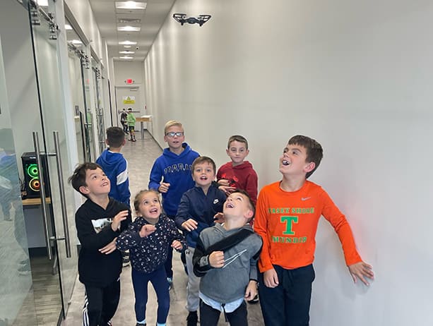 Children follow a drone they've programmed on an automated flight path using Python